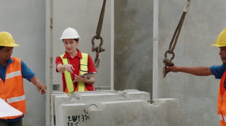 The expert chief engineer is walking around inspecting the work of the workers. and provide guidance on correct work to workers within the precast concrete slab factory.